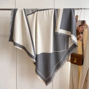 Detalle de bufanda de retazos gris y beige con flecos largos en un elegante look otoñal