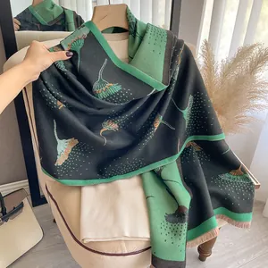 Detailed view of thick cashmere-like scarf with dandelion patterns and orange tassels