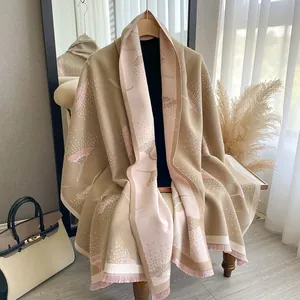 Detail of soft knit shawl with pink floral jacquard pattern and tassel trim finish