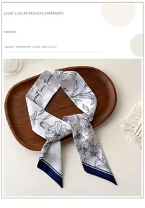 Detalle de pañuelo de seda floral con lirios y bordes azul oscuro en bandeja de madera