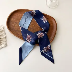 Détail d'un foulard en soie à fleurs avec texte posé sur un plateau en bois