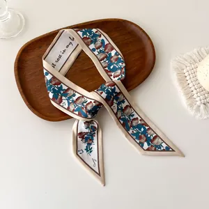Detail van een smalle zijden sjaal met rozen en muzieknoten print op een houten plateau