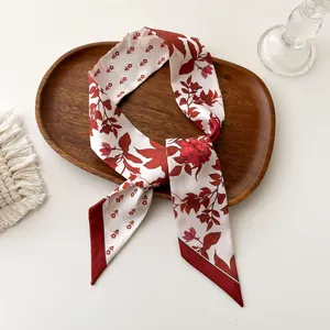 Détail d'un twilly en satin à fleurs avec roses rouges sur un plateau en bois