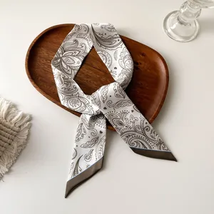Détail d'un foulard en soie Paisley beige élégamment placé sur un plateau en bois