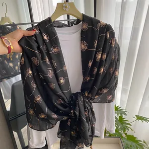 Detail of black lightweight scarf showing gold dandelion pattern and sheer texture