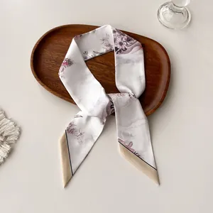 Detail shot of a slim floral twilly scarf on a wooden tray with soft lighting