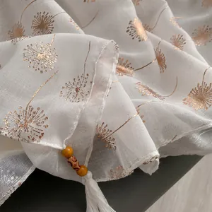 Detail of white dandelion scarf with golden prints and ethnic wood bead tassels