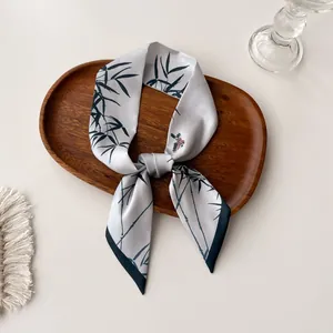 Detail of silk-like twilly scarf with elegant bamboo leaves and bird print on a tray