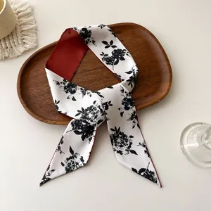 Gros plan d'une écharpe en soie double face avec imprimé floral et revers rouge foncé