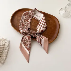 Detail van elegante bedrukte zijden sjaal geknoopt in een strik op houten dienblad