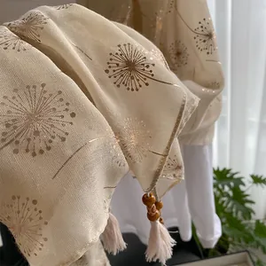 Detail of dandelion gold foil pattern on beige linen scarf with wooden bead tassels