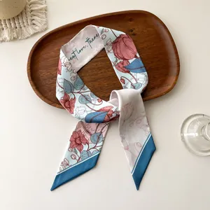 Vue détaillée d'un foulard en soie imprimé fleuri avec pointes sur plateau bois