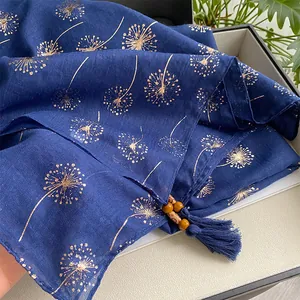 Detailed texture of dark blue cotton linen scarf with golden dandelion print and tassels