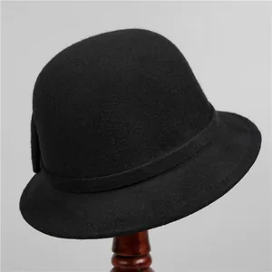 Detailed view of an elegant black wool felt cloche hat with ribbon on a vintage stand