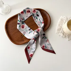 Détail d'un foulard en satin à motif floral de roses sur plateau en bois