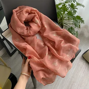 Detail of pink cotton linen scarf with gold dandelion print on a dark leather chair