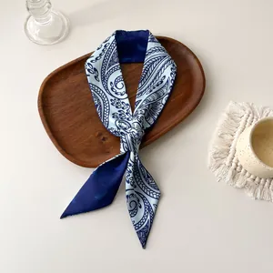 Détail d'un foulard en soie à motif paisley bleu sur un plateau en bois au style élégant