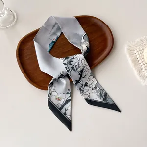 Detailed close-up of a blue floral silk skinny scarf with crane and magnolia patterns