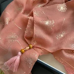 Detail of coral pink cotton scarf with gold dandelion pattern and beaded tassel fringe