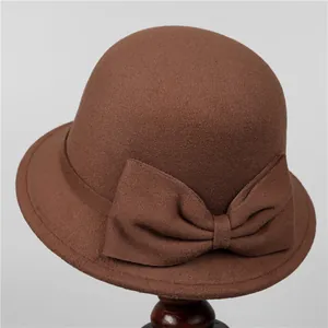 Elegant Audrey Hepburn style brown wool cloche hat with a bow on a wooden stand