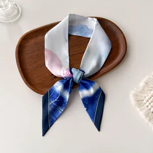 Close-up of abstract watercolor silk scarf tied on a wooden tray with soft lighting