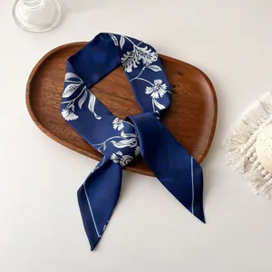 Vue détaillée macro du foulard twilly à fleurs bleu marine sur un plateau en bois rustique