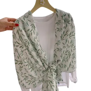 Elegant cotton linen scarf with green leaf pattern knotted over a white long-sleeve tee