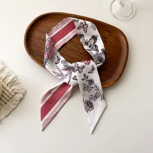 Détail d'un foulard en soie twilly avec imprimé fleuri et papillon sur un plateau décoratif