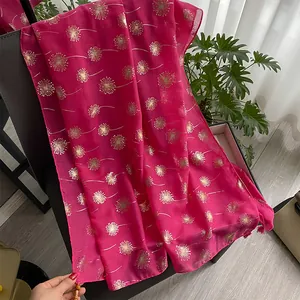 Detail of rose red linen scarf featuring golden dandelion patterns and beaded tassels