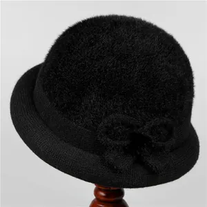 Close-up of black plush winter hat featuring a stylish bow and knitted brim detail