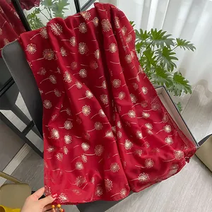 Detail of red floral scarf with golden dandelion print and beaded tassels on a chair