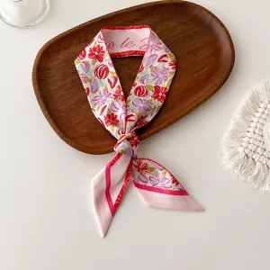 Detailweergave van de roze zijden sjaal met bloemenprint en rode gestikte randen