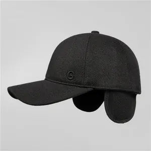 Men's winter baseball cap with ear flaps in black wool blend, side view with G. embroidery