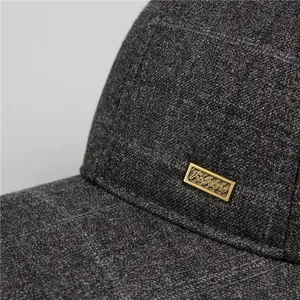 Dettaglio ravvicinato del cappellino grigio scuro in misto lana con logo in metallo