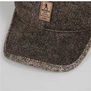 Detail of winter baseball cap showing herringbone tweed fabric and embossed faux leather patch