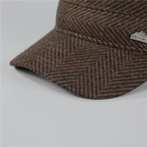 Macro shot of brown herringbone wool fabric and a detailed metal mountain badge on the winter hat