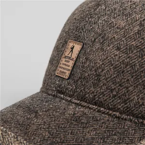 Detail of winter baseball cap showing dark brown tweed texture and leather patch