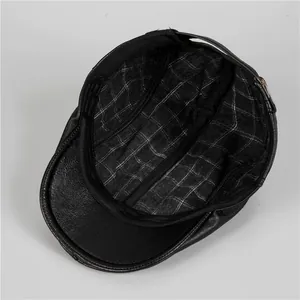Detail view of the black leather flat cap with plaid lining and metal buckle