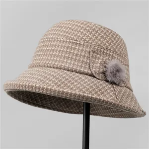 Dettaglio del cappello alla pescatora a quadri con decorazione a pompon grigio