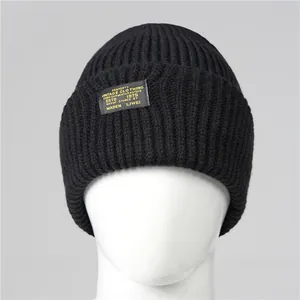Close-up of black ribbed knit beanie with vintage clothing yellow text woven label