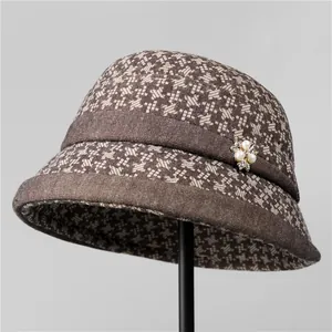 Detail of winter cloche hat with houndstooth pattern and elegant pearl flower brooch
