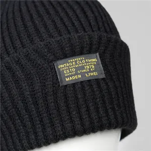 Detailed close-up of a black knit beanie featuring a vintage-style rectangular woven label