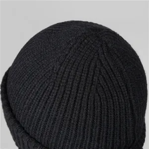 Close-up of black ribbed knit beanie showing detail of the stitching and crown