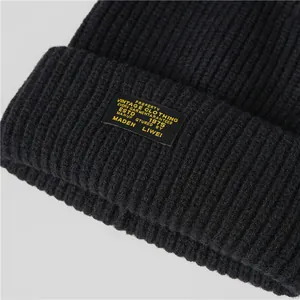 Close-up of black ribbed knit balaclava with a vintage woven Maden brand label detail