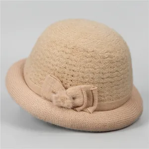 Detailed knit texture of a warm beige elderly women's bucket hat with a bow and pom-pom