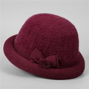Detail of wine red winter hat featuring velvet bow decoration and plush texture