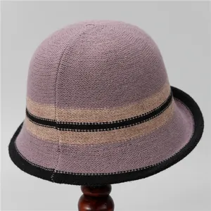 Detail of dusty pink knitted bucket hat with striped accent on a wooden display stand