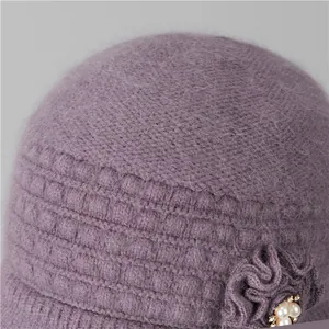 Detalle de gorro de punto morado en pelo de conejo con adorno de flor y perlas
