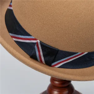 Close-up of khaki wool felt hat featuring a navy striped ribbon on a wooden stand