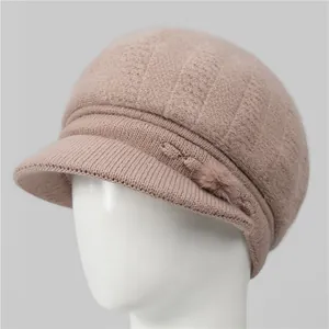 Detalle del gorro de punto rosa con pompón de piel sintética y lazo lateral
